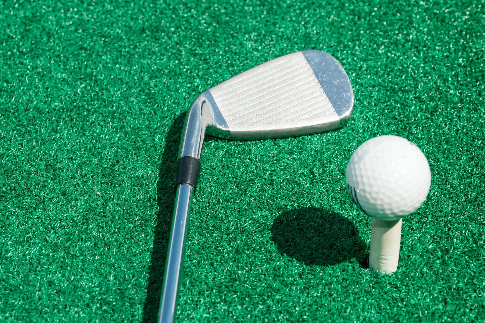 golf club and ball on a stand with artificial turf