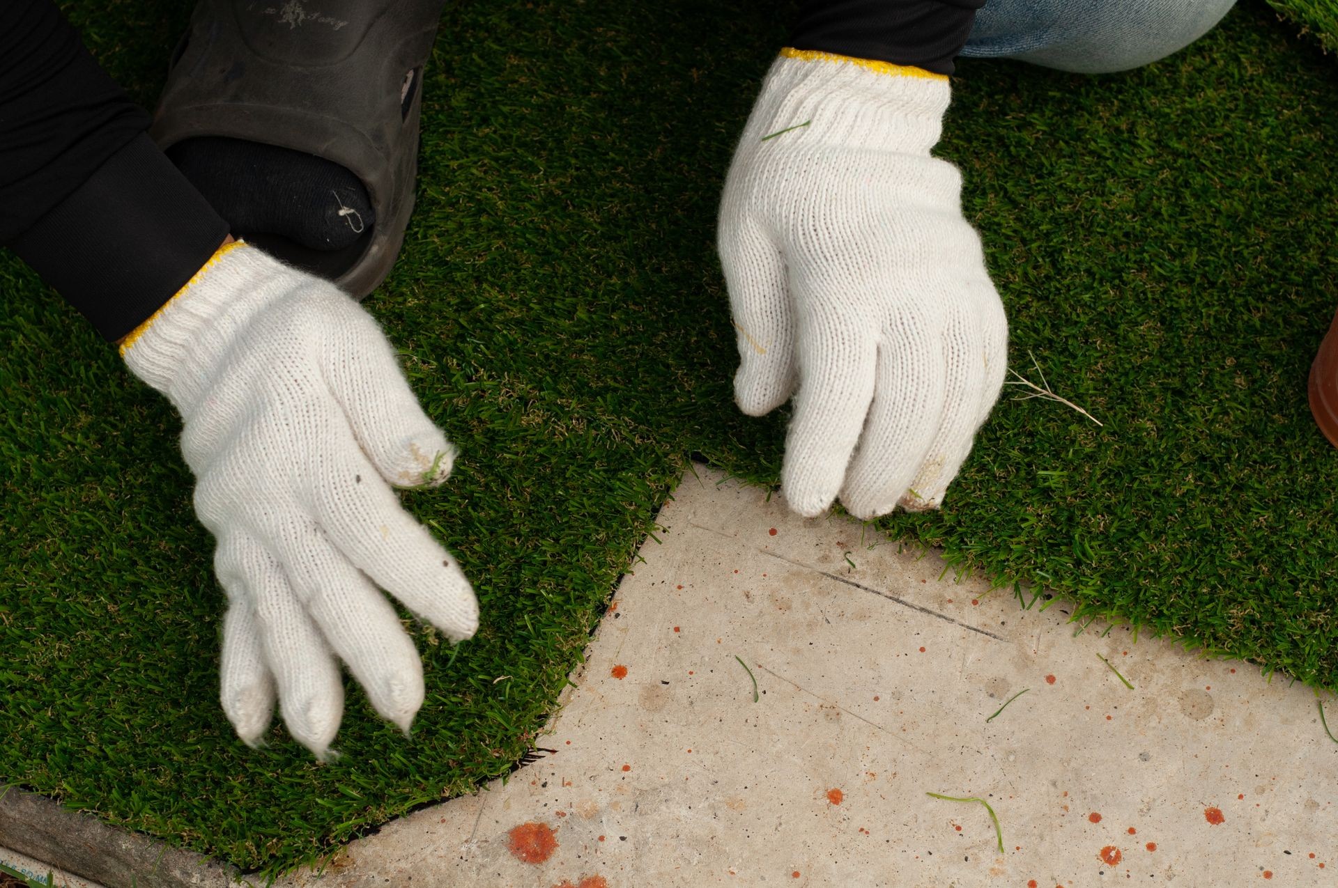Stick with glue artificial turf grass on floor. Worker install green grass